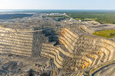 Vue aérienne d'une mine à ciel ouvert, avec ses gradins et ses installations de surface.